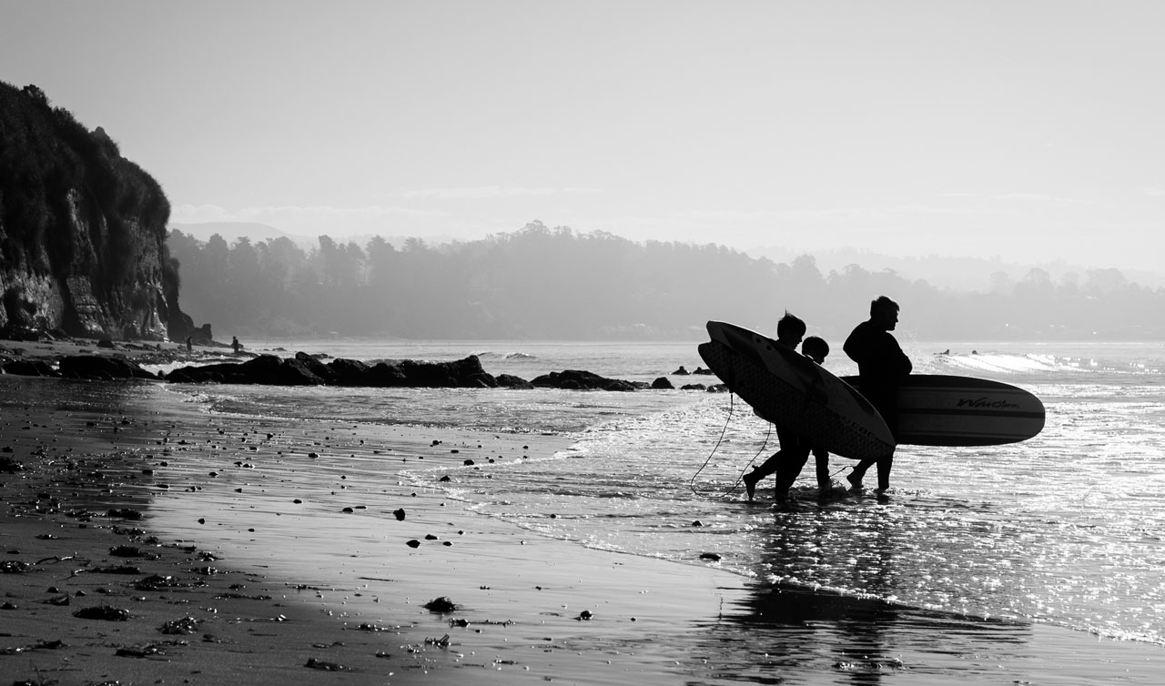 Surfing family walking into ocean