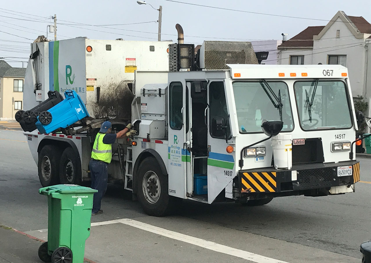 Waste collector dumping trash and recycling into truck.